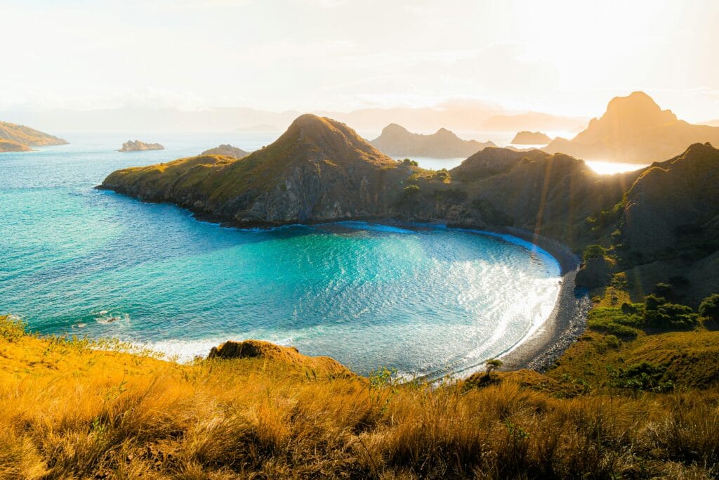 A panoramic overview of the rugged volcanic hills and bright turquoise waters of Komodo National Park near Flores, Indonesia.